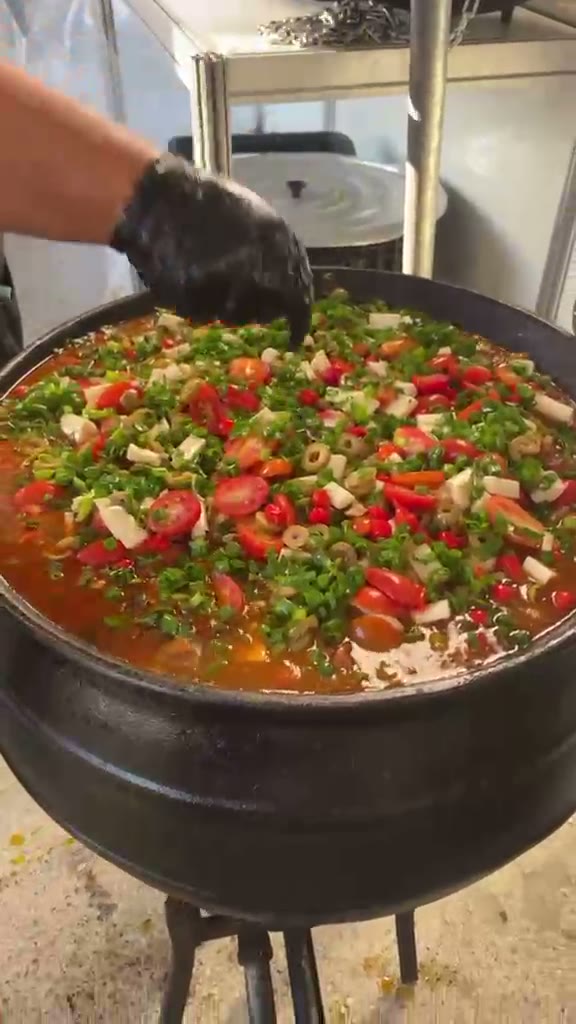 Carreteiro fumegante na panela de ferro, finalizado com tomate, pimenta e cebolinha